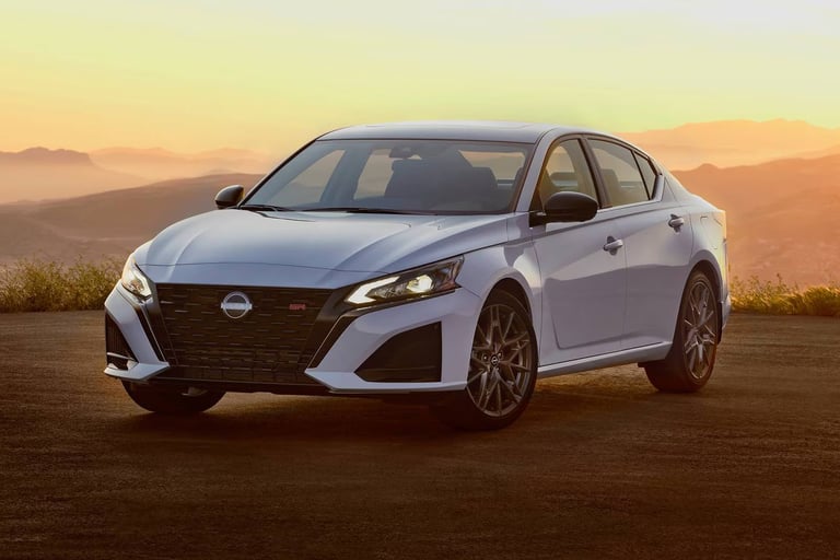 White Nissan sedan parked on desert terrain with golden sunset and mountains in the background
